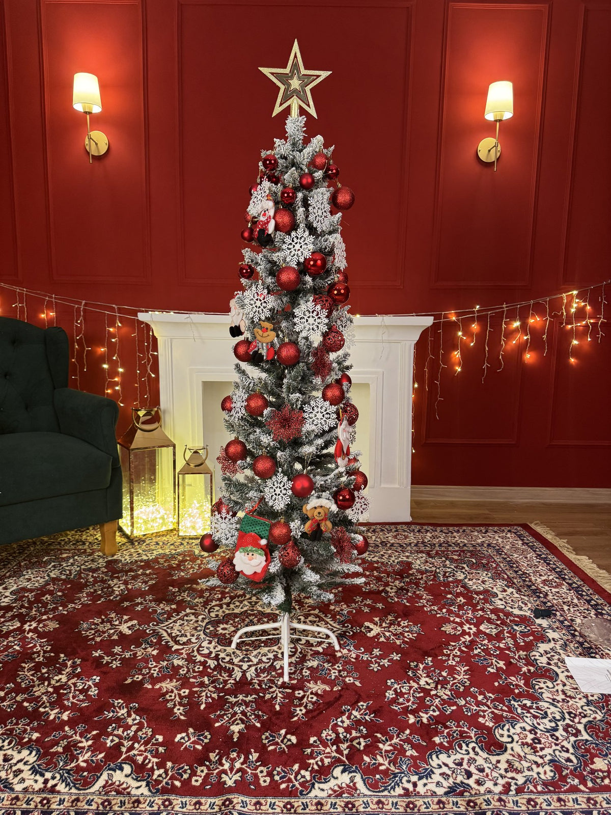 Árvore slim nevada de 1,50 m decorada com bolas vermelhas e prateadas e estrela dourada, em sala com parede vermelha, lareira e tapete