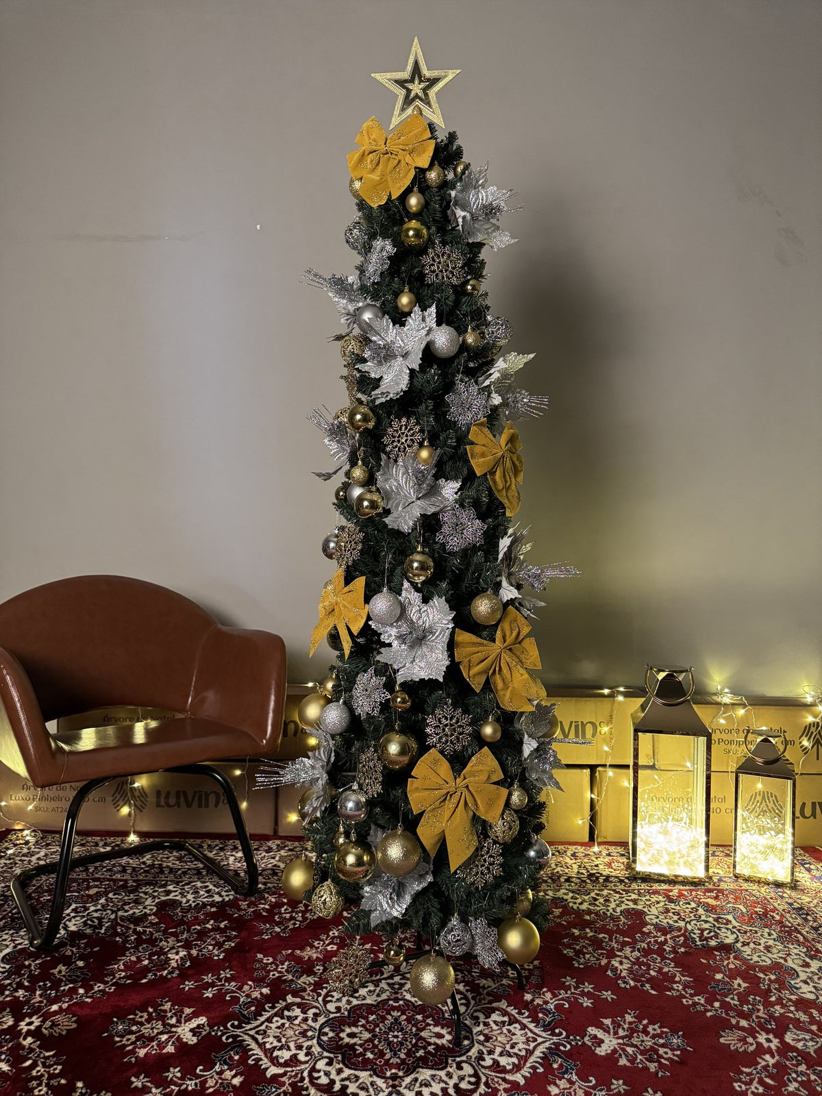 Árvore slim de 1,80 m decorada com laços dourados, flores prateadas e estrela, com lanternas e luzes ao lado