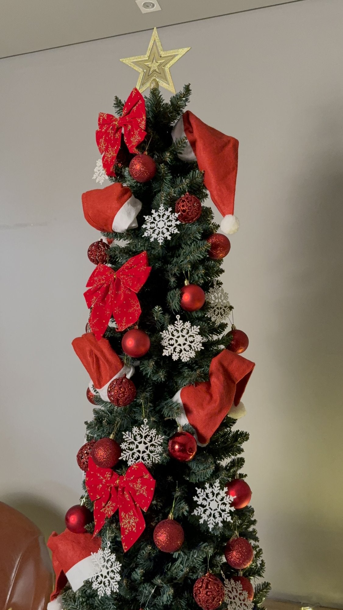 Árvore slim de 2,10 m decorada com laços e bolas vermelhas, flocos prateados e estrela, em detalhe