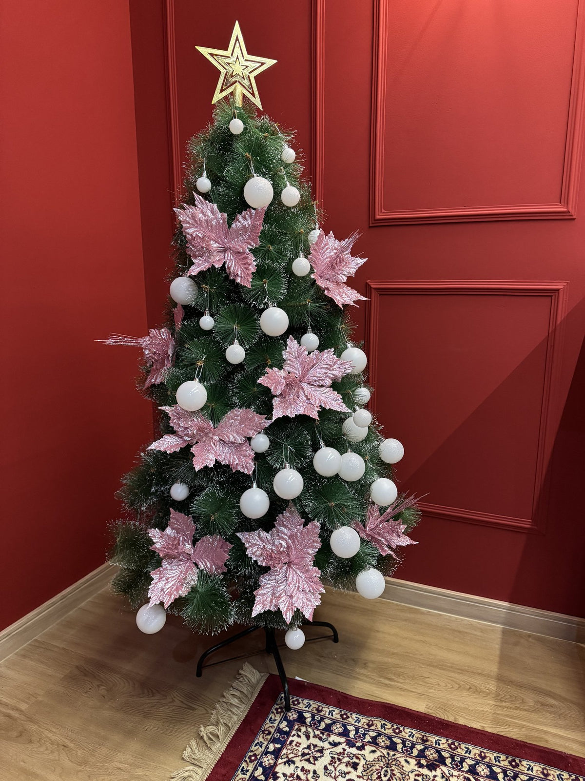 Árvore pompom com pontas nevadas de 1,50 m decorada com bolas brancas, flores rosa e estrela dourada, vista mais próxima
