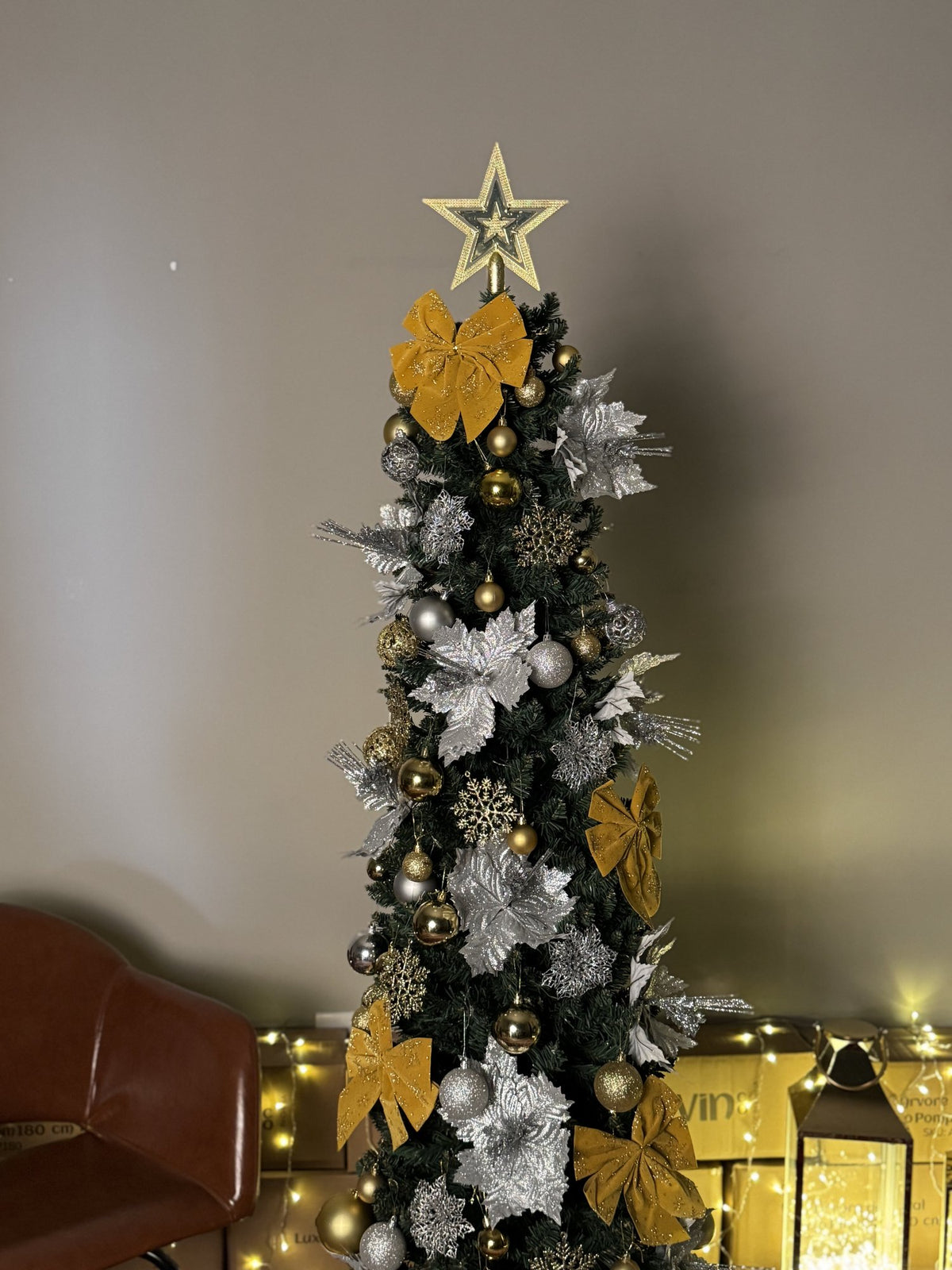 Árvore slim de 1,80 m decorada com laços dourados, flores prateadas e estrela, em detalhe