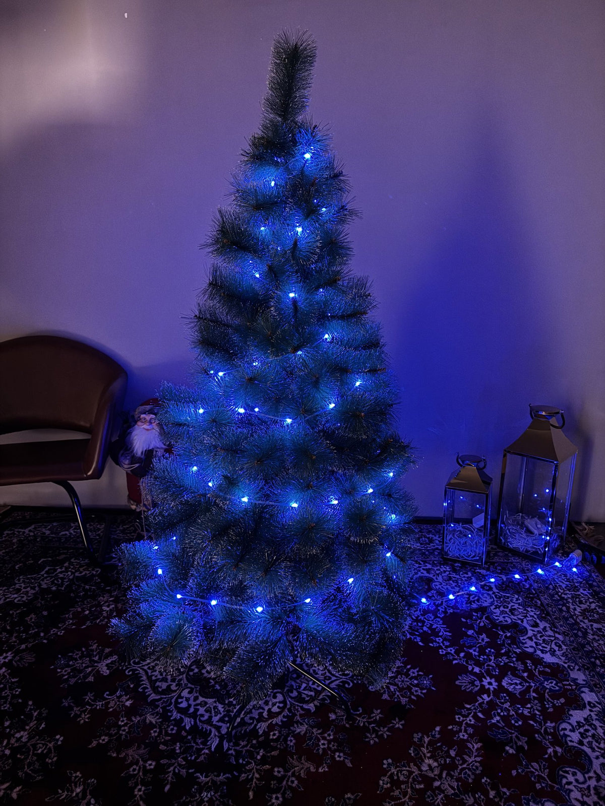 Árvore pompom com pontas nevadas de 1,50 m com pisca-pisca de luz azul em ambiente escuro