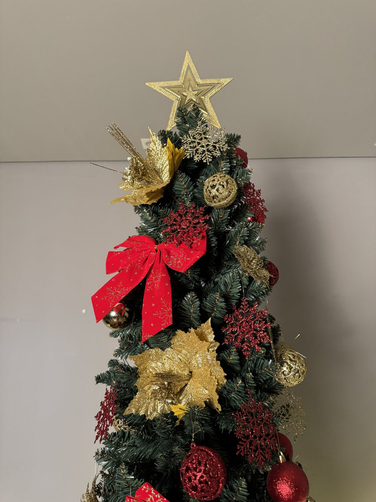 Árvore slim de 2,40 m topo decorado com laço vermelho, flores douradas, bolas e estrela dourada